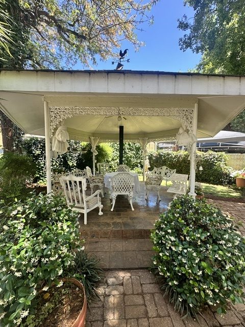 White ironwork gazebo with outdoor seating in the garden